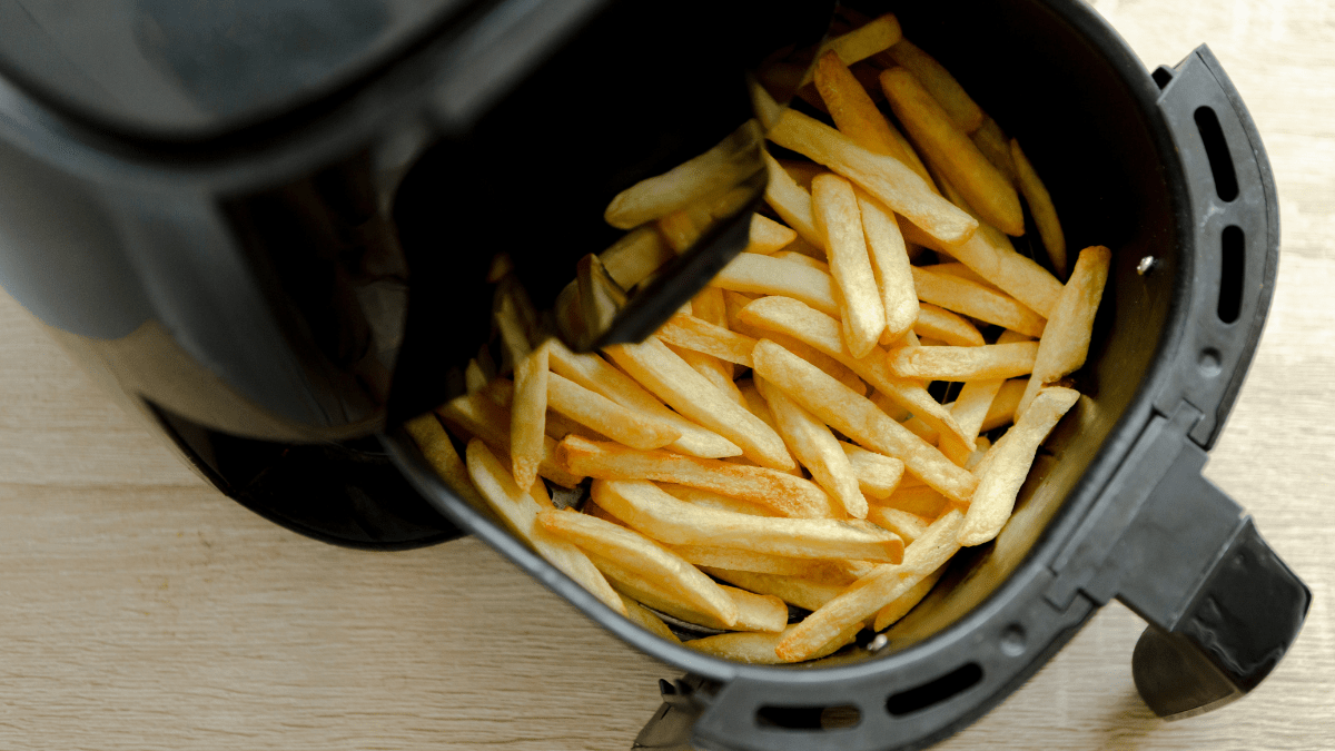 A close up of an air fryer which contains fries